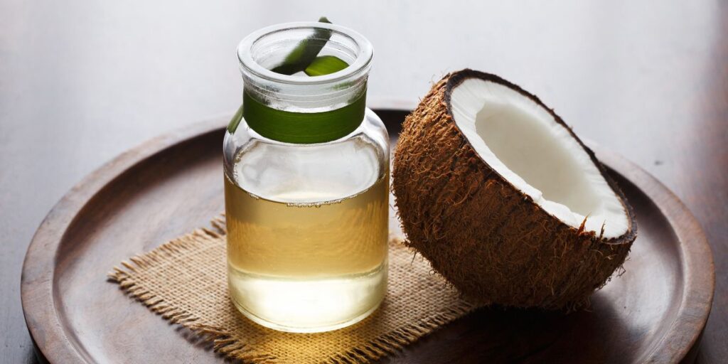 half coconut beside coconut oil in a small jar - coconut oil for dry nose 