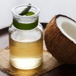 half coconut beside coconut oil in a small jar - coconut oil for dry nose