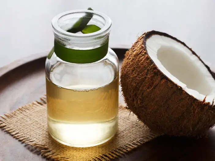 half coconut beside coconut oil in a small jar - coconut oil for dry nose